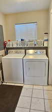 Washroom featuring a textured ceiling, laundry area, tile patterned flooring, and washing machine and clothes dryer