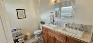 Full bathroom with tile patterned flooring, double vanity, toilet, and a sink