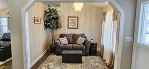 Living area with a wealth of natural light, baseboards, arched walkways, and dark wood-style flooring