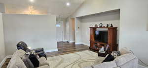 Living room featuring recessed lighting, baseboards, lofted ceiling, and dark wood-style floors