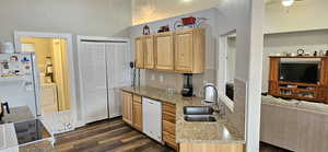 Kitchen with light brown cabinets, a sink, light stone counters, dark wood finished floors, and white appliances