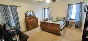 Bedroom with baseboards, light colored carpet, and a ceiling fan