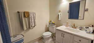 Full bathroom featuring vanity, tile patterned floors, toilet, and baseboards