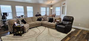 Living room featuring dark wood-type flooring, baseboards, and lofted ceiling