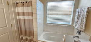 Bathroom featuring a tub with jets and a shower with curtain