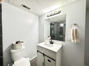 Full bathroom featuring visible vents, toilet, a tile shower, a paneled ceiling, and vanity