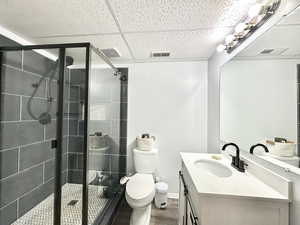 Bathroom with visible vents, a stall shower, and wood finished floors