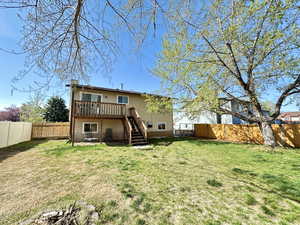 Rear view of property featuring a fenced backyard, a wooden deck, a lawn, and stairs