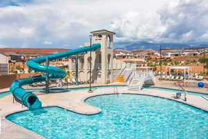 Pool featuring a patio, fence, playground community, a water slide, and a mountain view