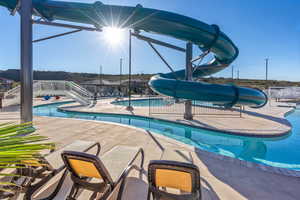 Pool with glass enclosure, a patio, fence, and a water slide