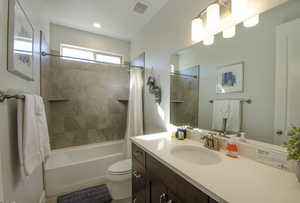 Bathroom with visible vents, toilet, shower / bath combo with shower curtain, and vanity