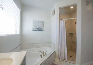 Bathroom featuring a bath, a stall shower, and vanity