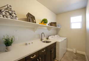 Laundry room with a sink, baseboards, cabinet space, and separate washer and dryer