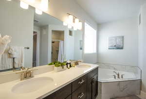 Bathroom with curtained shower, double vanity, a bath, and a sink