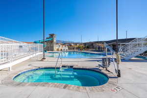 Community pool with a patio area, fence, and a hot tub