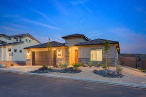 Prairie-style house featuring stucco siding, driveway, stone siding, fence, and an attached garage