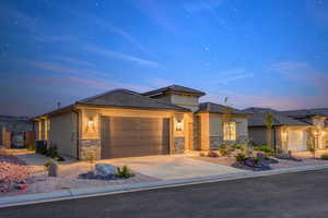 Prairie-style home featuring central air condition unit, stucco siding, stone siding, concrete driveway, and a garage