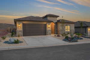 Prairie-style house with concrete driveway, an attached garage, stone siding, and stucco siding