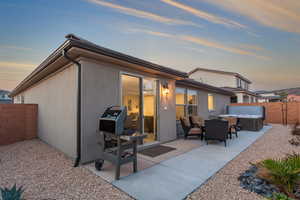 Back of house at dusk with a patio area, a fenced backyard, and a hot tub