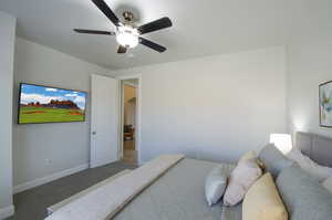 Carpeted bedroom with baseboards, arched walkways, and ceiling fan