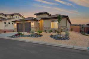 View of front of house featuring stucco siding, stone siding, driveway, and fence