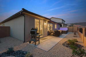 Back of property at dusk featuring a patio area, a hot tub, and a fenced backyard