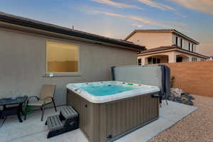 Patio terrace at dusk featuring fence and a hot tub