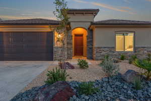 View of front facade featuring stucco siding, stone siding, a garage, and concrete driveway