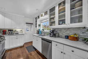 Kitchen featuring appliances with stainless steel finishes, white cabinetry, light countertops, and a sink