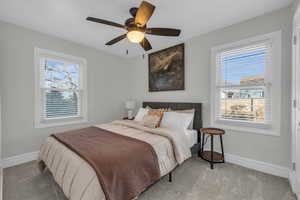 Carpeted bedroom with ceiling fan and baseboards