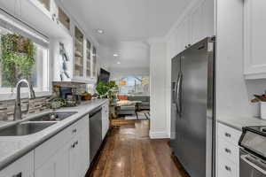 Kitchen with a sink, ornamental molding, decorative backsplash, stainless steel appliances, and dark wood-style flooring