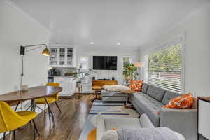 Living area with dark wood-type flooring, recessed lighting, and ornamental molding