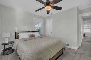 Bedroom featuring visible vents, light colored carpet, a ceiling fan, and baseboards