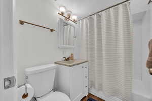 Full bathroom with toilet, vanity, and shower / bath combination with curtain