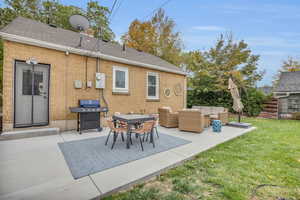 Back of house featuring a yard, roof with shingles, an outdoor hangout area, brick siding, and a patio area