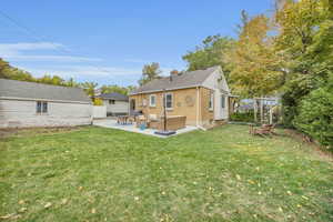 Rear view of property with fence, a yard, brick siding, a chimney, and a patio area