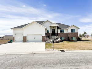 View of front of property featuring a garage, driveway, brick siding, and a front lawn