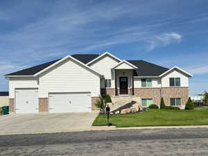 View of front of home featuring brick siding, a front lawn, an attached garage, and concrete driveway