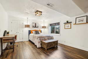 Bedroom with dark wood-style floors, visible vents, a textured ceiling, and baseboards