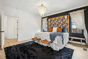 Bedroom featuring wood finished floors, a chandelier, and ornamental molding