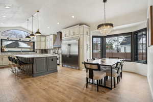 Kitchen with premium range hood, light countertops, vaulted ceiling, high quality appliances, and a center island