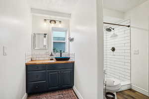 Full bath featuring toilet, a stall shower, wood finished floors, baseboards, and vanity