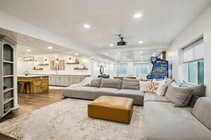 Living area featuring recessed lighting, bar area, a textured ceiling, and wood finished floors