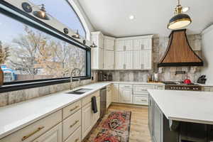 Kitchen with custom exhaust hood, a sink, tasteful backsplash, stove, and dishwasher