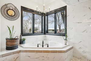 Full bath featuring a bath, an inviting chandelier, and ornamental molding