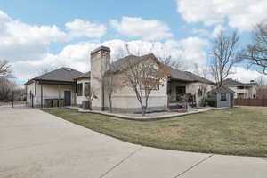 Exterior space with fence, concrete driveway, a front yard, central AC unit, and a chimney