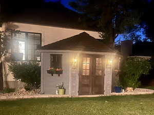 View of front of home featuring an outdoor structure, a yard, and stucco siding