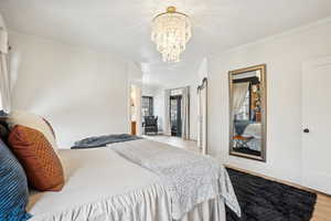 Bedroom with crown molding, a notable chandelier, and wood finished floors