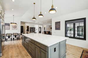 Kitchen featuring vaulted ceiling, light wood-style floors, built in appliances, and a kitchen island