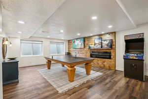 Game room featuring recessed lighting, a large fireplace, a textured ceiling, and wood finished floors